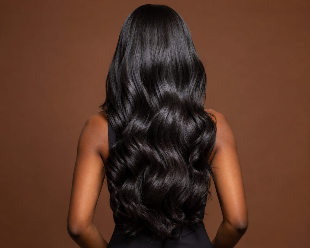 Model with long, wavy, natural-looking hair extensions seen from behind